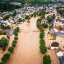 Overhead view of a flooded area with homes and trees surrounded by brown water