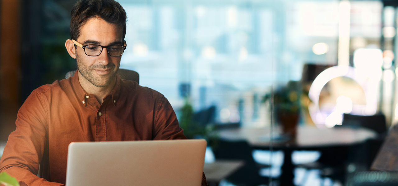 Une personne assise et souriante travaillant sur un ordinateur portable