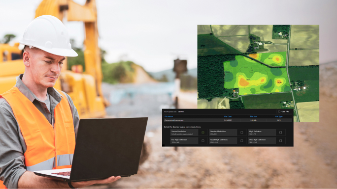 A construction worker in a white hard hat looking at a laptop with an inset digital image of a green field