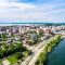 An aerial image of a sunny tree-filled city bordered on two sides by peaceful blue lakes