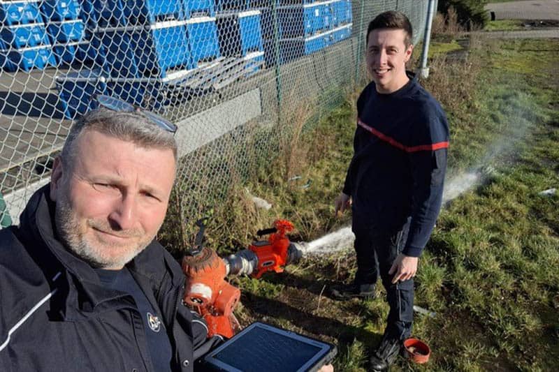 Two people workin in the field looking at the camera.