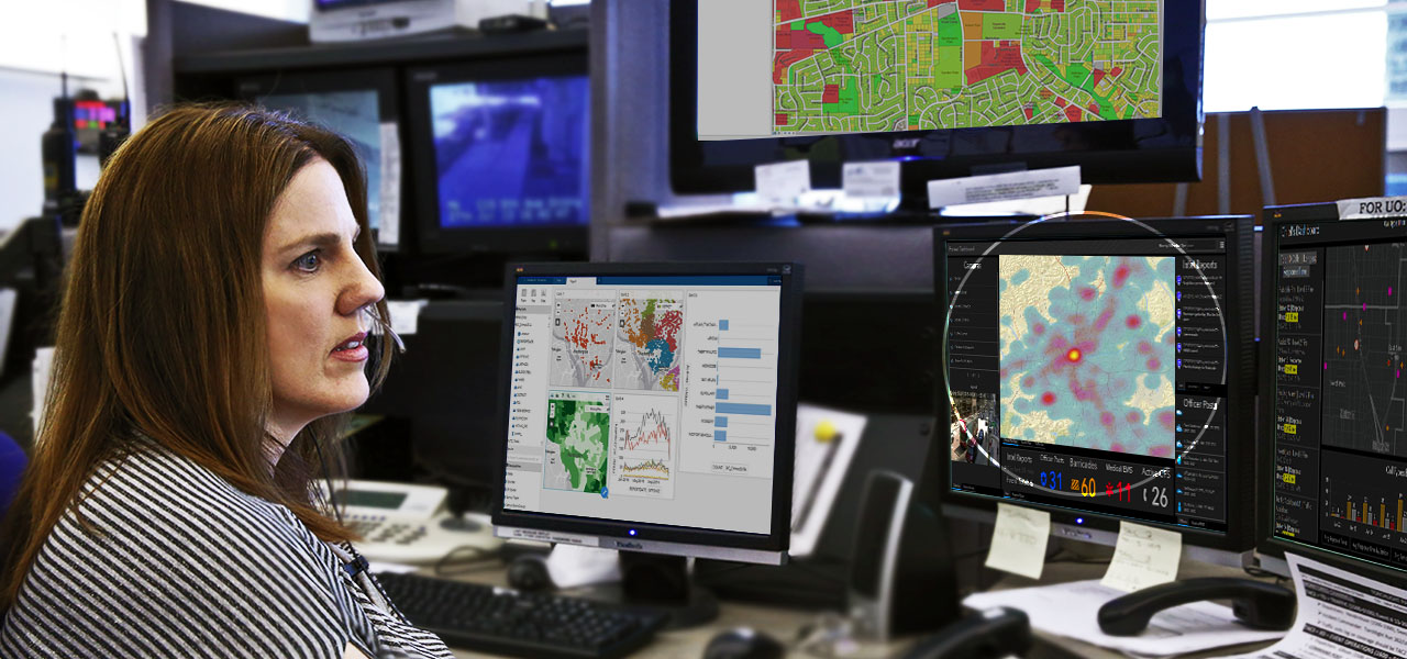 Woman in emergency services sitting behind computer monitors