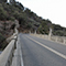 An old, two-lane concrete bridge in a mountainous landscape with a lot of shrubbery