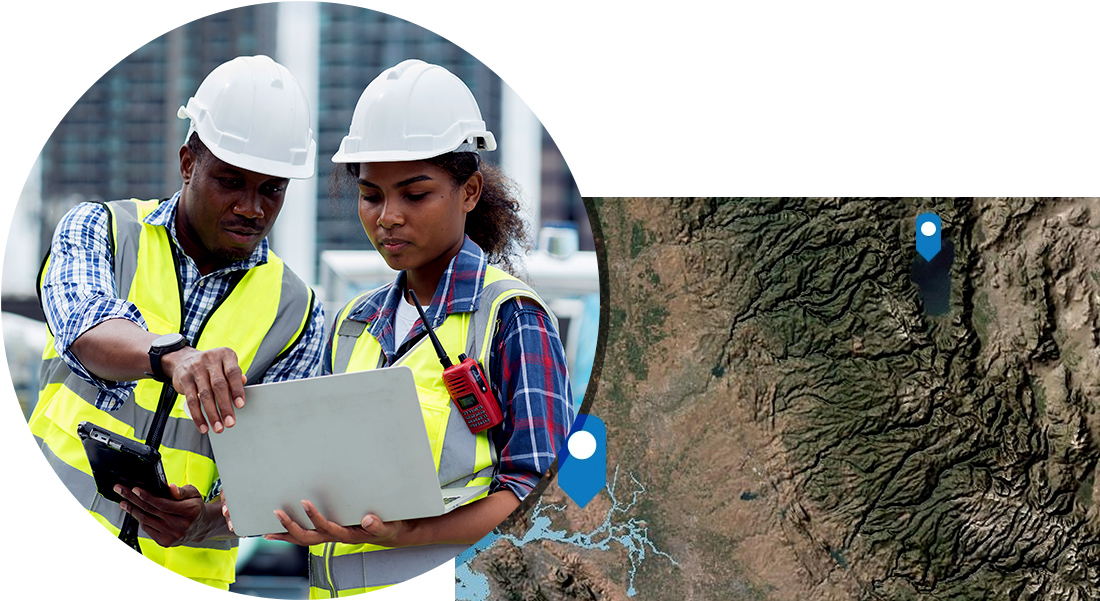 Two workers in white hard hats looking at a mobile device and blue GPS markers shown in a satellite map