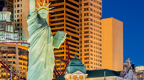 A view of the City of Las Vegas, including tall buildings, a rollercoaster, and the Replica of the Statue of Liberty