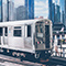 Two elevated L train tracks with two rail cars surrounded by modern, high-rise buildings in downtown Chicago