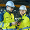 Two utility workers at a work site looking at data on a tablet