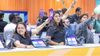 A large group of student assistants posing in the registration area at a modern convention center