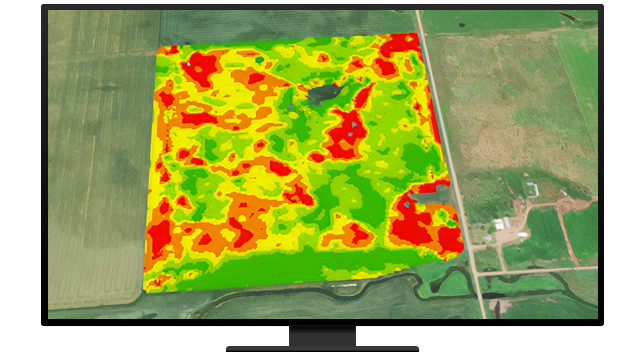 A composite aerial photo of green farmland with an overlaid heat map in brighter green, orange, and red