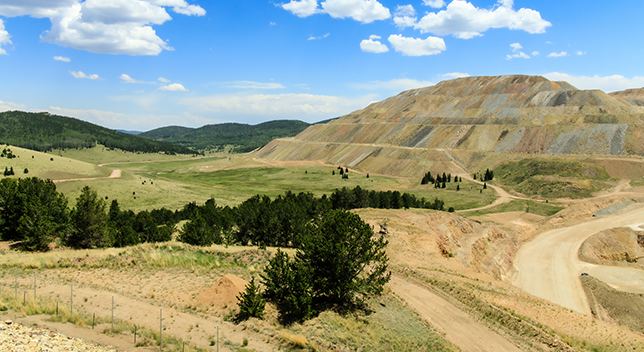 An aerial view of a deep quarry with green landscape surrounding it