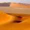 Expansive, sun-soaked sand dunes under a clear sky