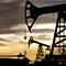 A photo of a field of pumpjacks silhouetted against a pale cloudy sky