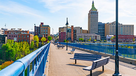 A pedestrian bridge in Miami with blue benches and buildings in the background