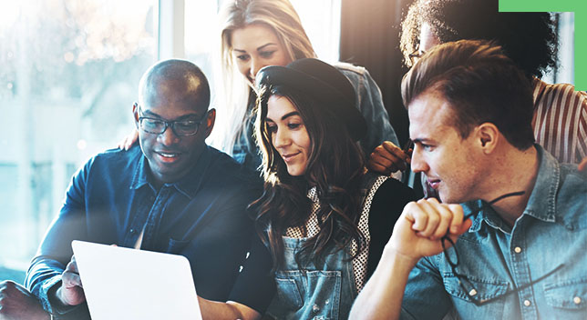 A diverse group of people looking at a laptop together