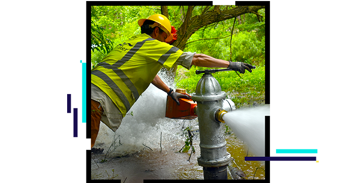 Person adjusting a fire hydrant that is dispersing water