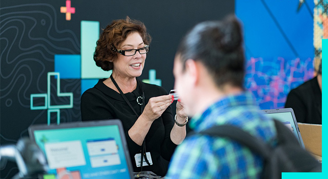 Person at a conference registration desk looking at a plastic card