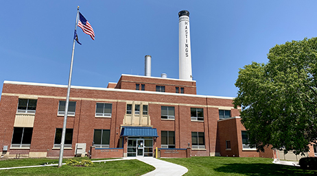 The façade of the Hastings Utilities building with a tree and flagpole in the foreground and a cloudless sky in the background