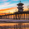 A peaceful coastline with a lifeguard tower on a dock silhouetted against a deep orange sunset