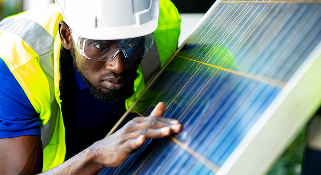 A fieldworker checking a solar panel install with his hand