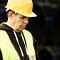 A fieldworker wearing a yellow hardhat and safety jacket