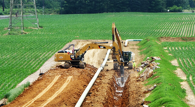 A green sign that reads “Wetland Boundary” in front of a pipeline