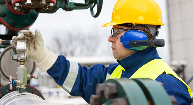 A pipeline operator checking a gas pressure meter