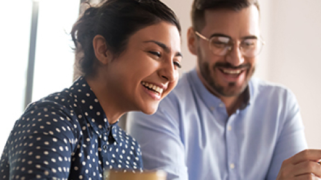 : A businessman and a businesswoman smile looking down at a document