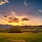 A green pasture leading to lush rolling hills at sunset